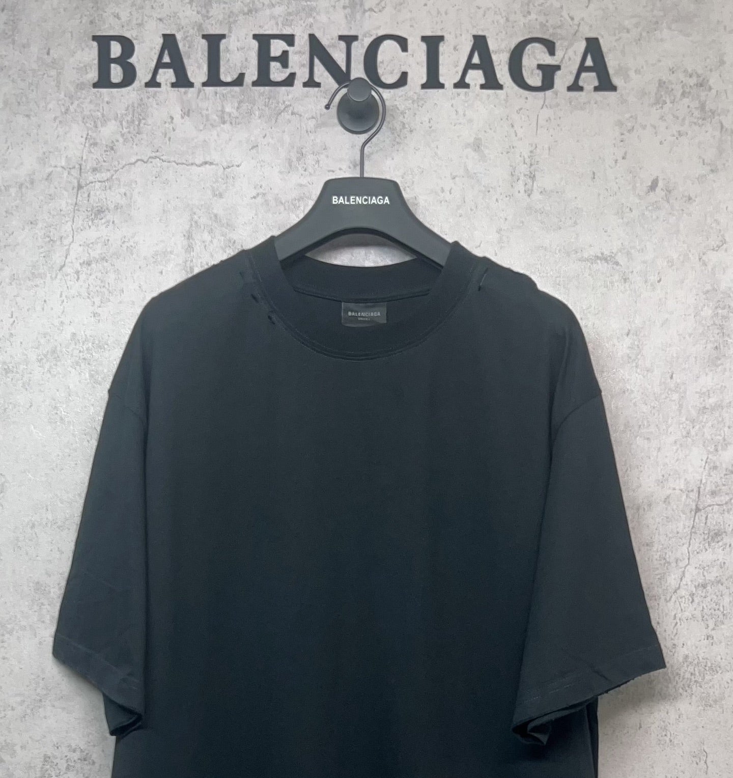 Black Balenciaga T-shirt close front view on hanger, crew neck and short sleeves.