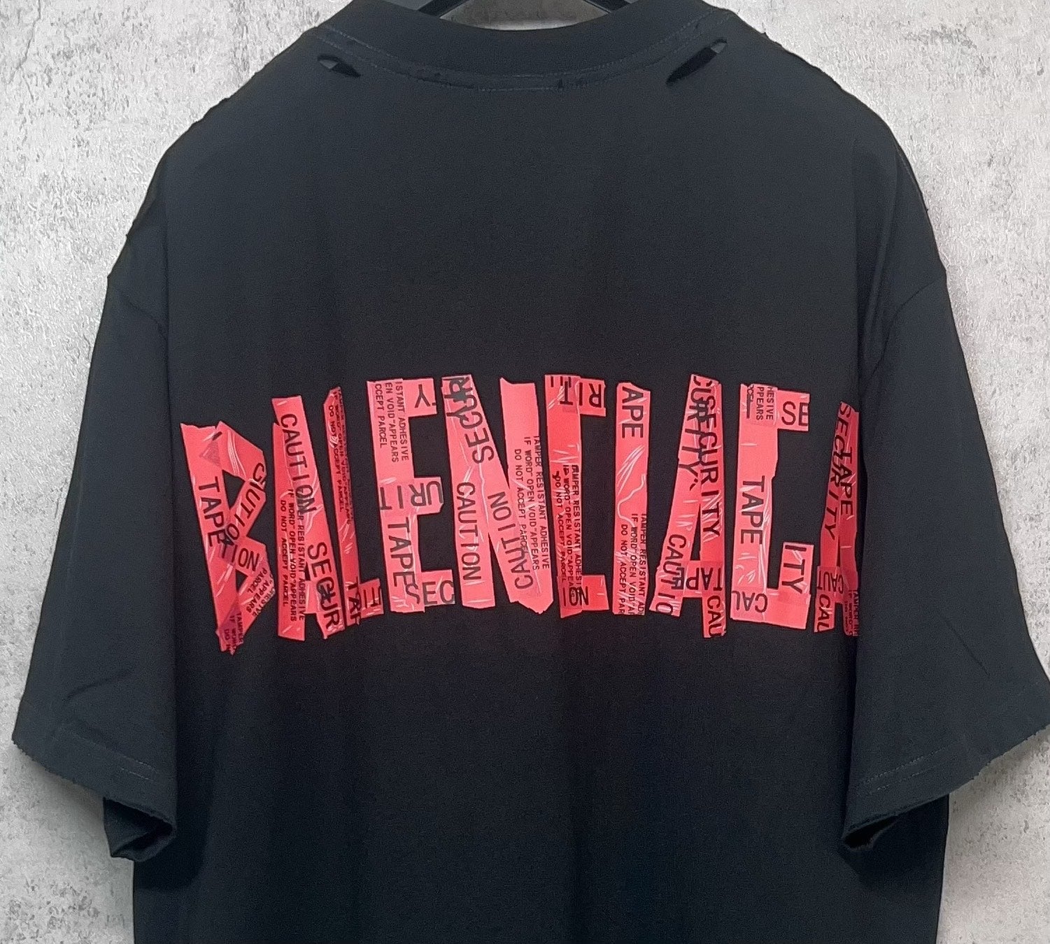 Black Balenciaga T-shirt back close-up with red graphic logo stripe text print.