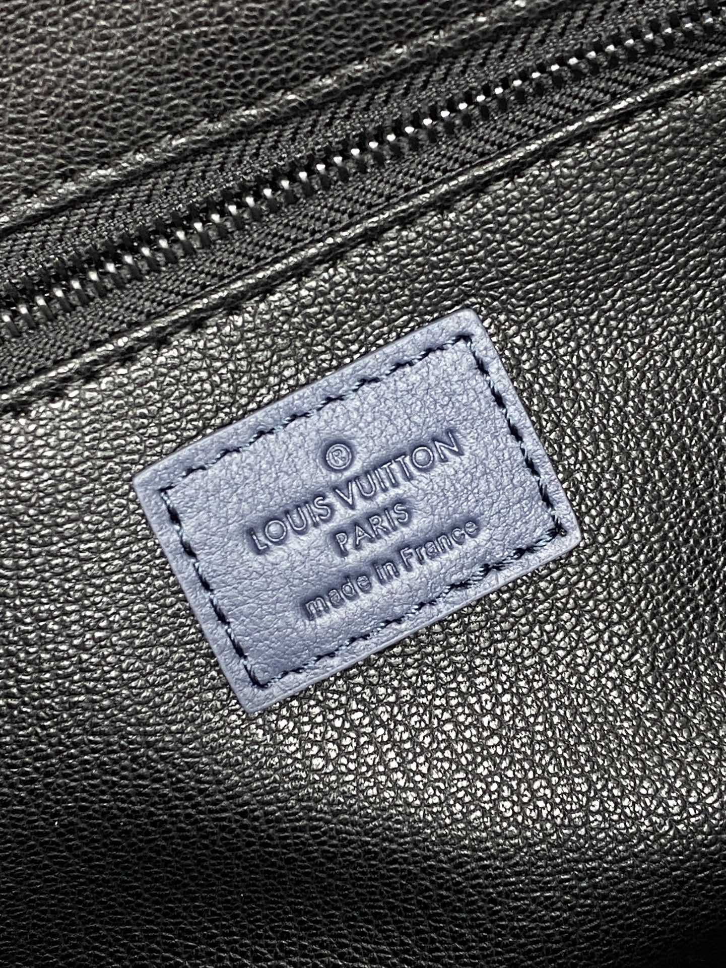 Louis Vuitton bag leather tag patch with Louis Vuitton and Paris imprint on dark blue surface
