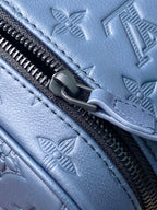 Louis Vuitton bag zipper area with dark blue leather pull and embossed monogram pattern