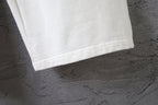 White pants with clean stitched hem at the ankle