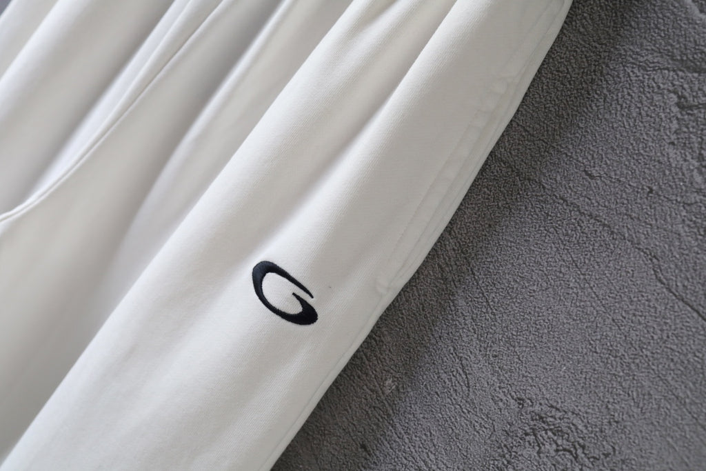 White pants leg with dark oval logo patch