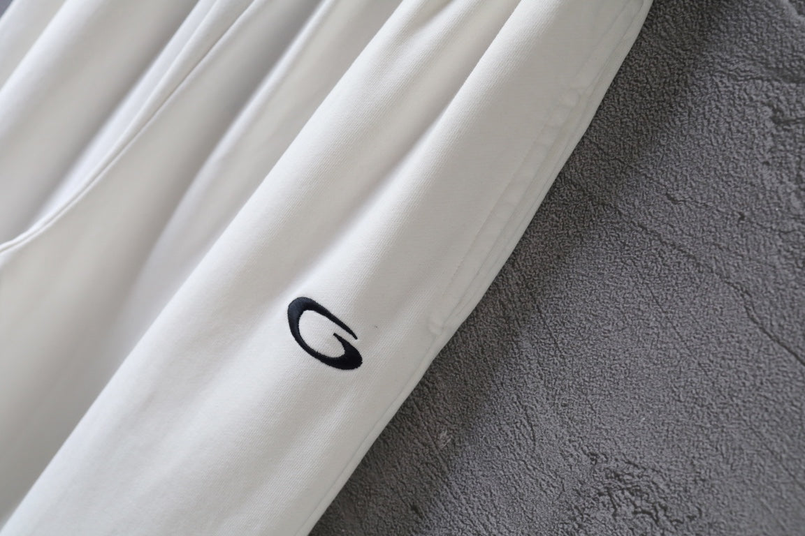 White pants leg with small black logo patch near the hem