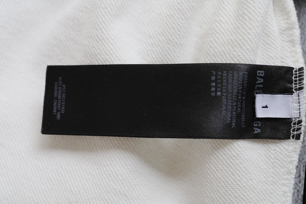 White pants with black brand care label inside near the hem