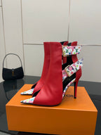 Red ankle boots with multicolor patterned strap cuff and gold-tone hardware; stiletto heel