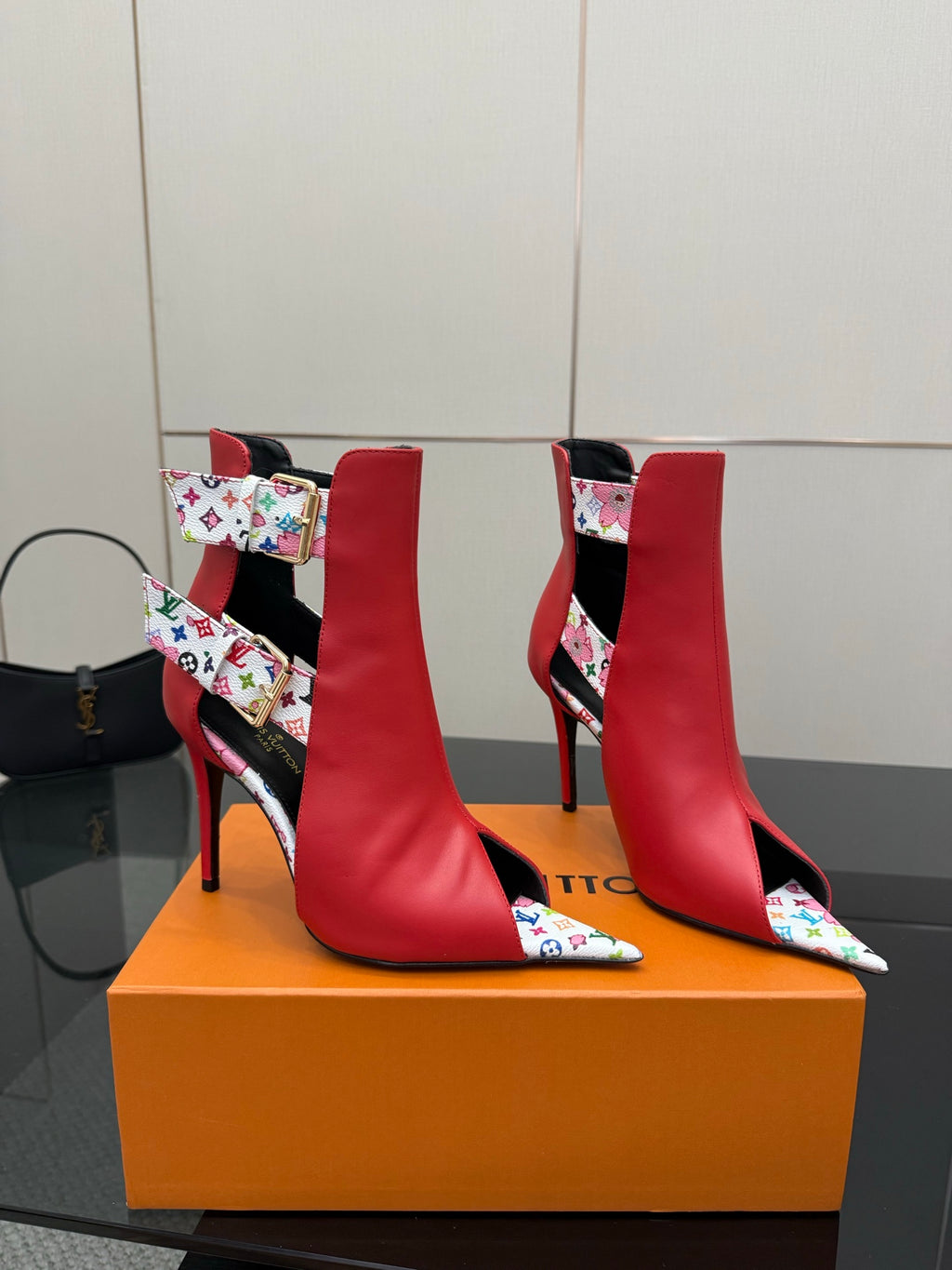Red ankle boots with multicolor logo-pattern panels, gold buckle detail, and stiletto heel