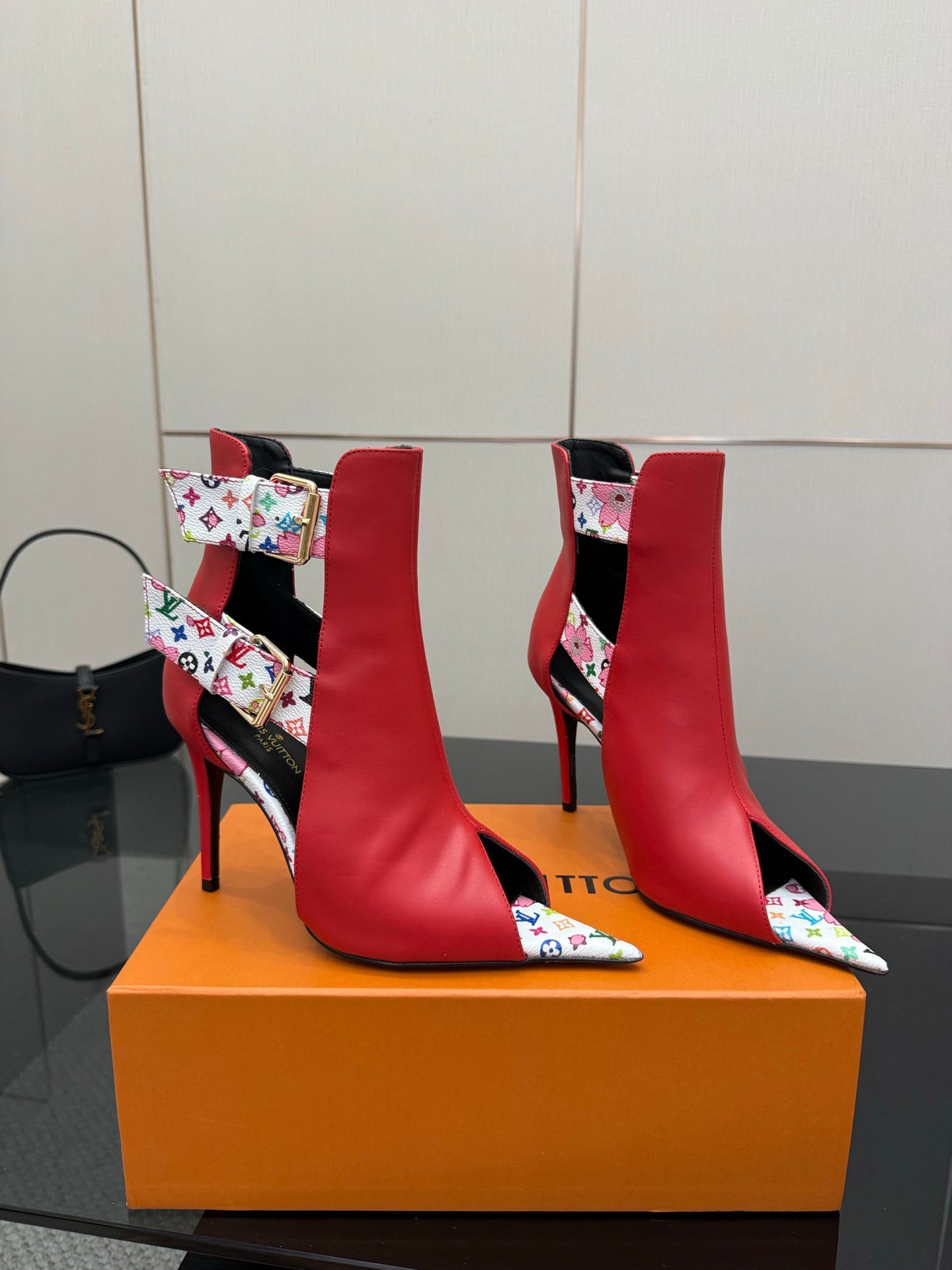Red ankle boots with multicolor logo-pattern panels, gold buckle detail, and stiletto heel