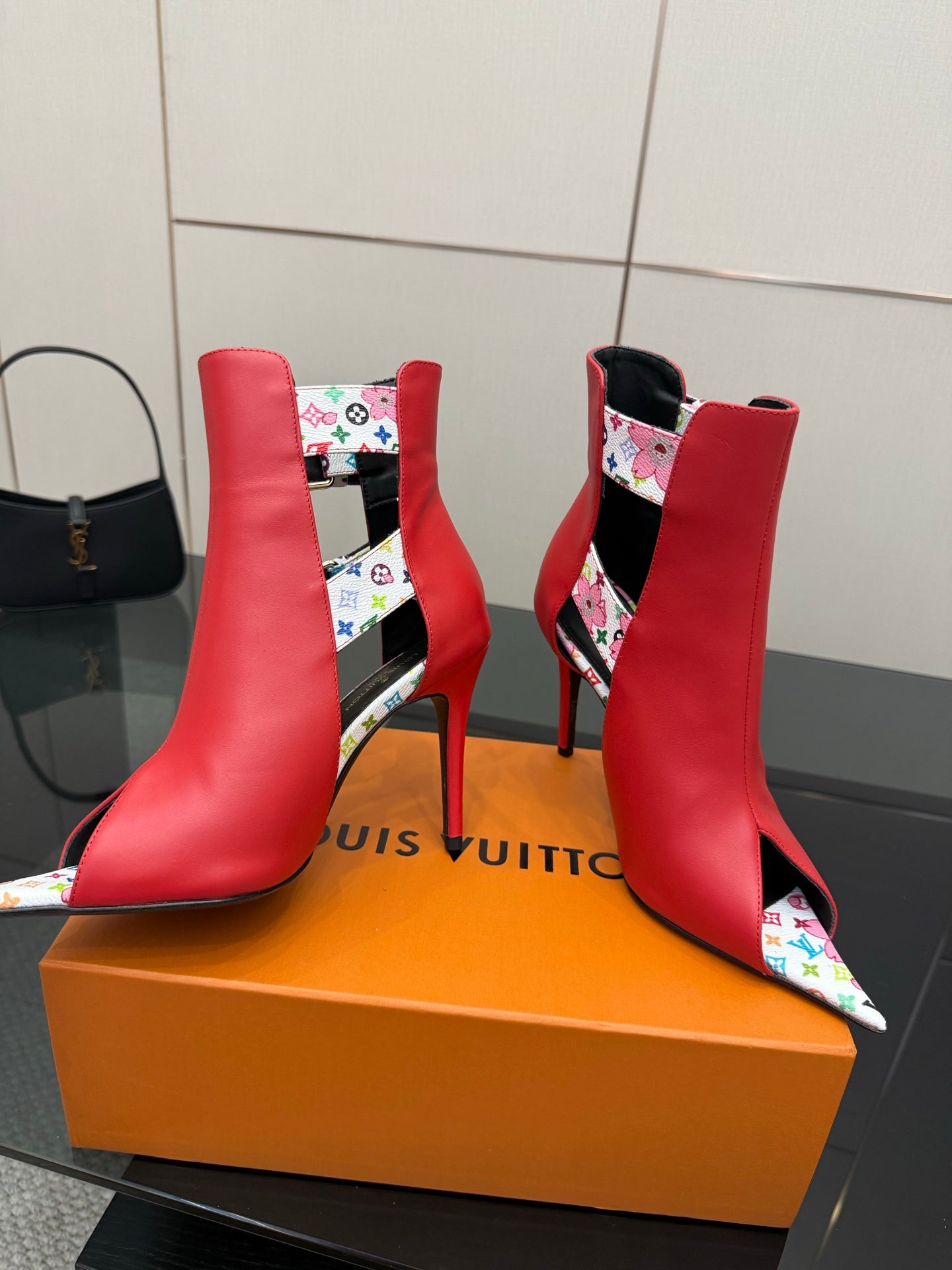 Red ankle boots with multicolor patterned straps and gold hardware, pointed toe, stiletto heel
