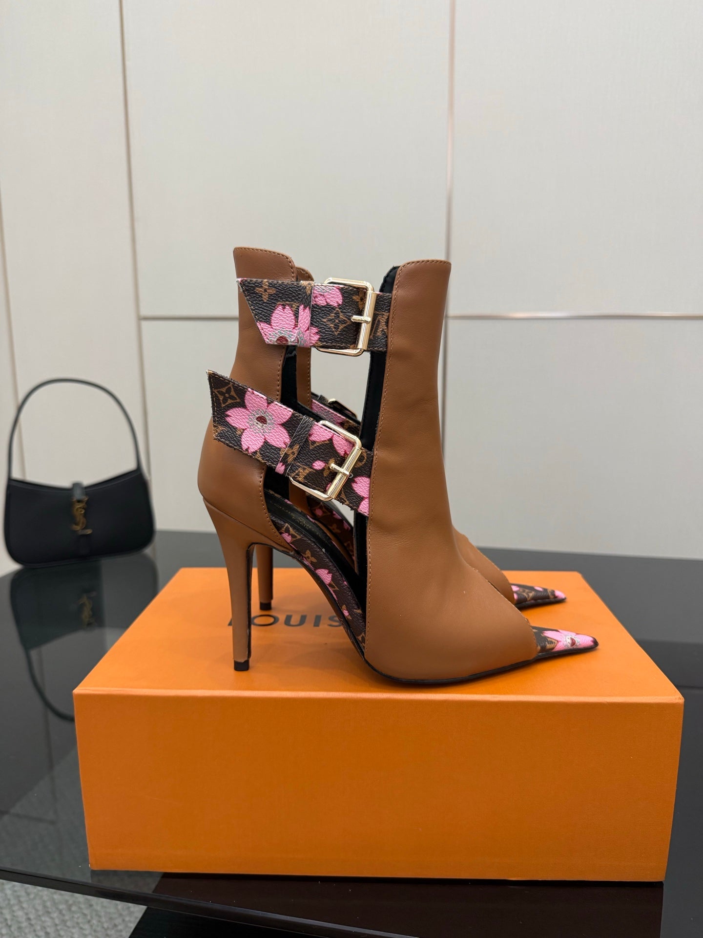 Women's Louis Vuitton ankle boots with tan leather, black floral straps, and tall stiletto heel.