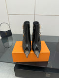 Black patent ankle boots with pointed toes, gold-tone buckle straps, stiletto heels.