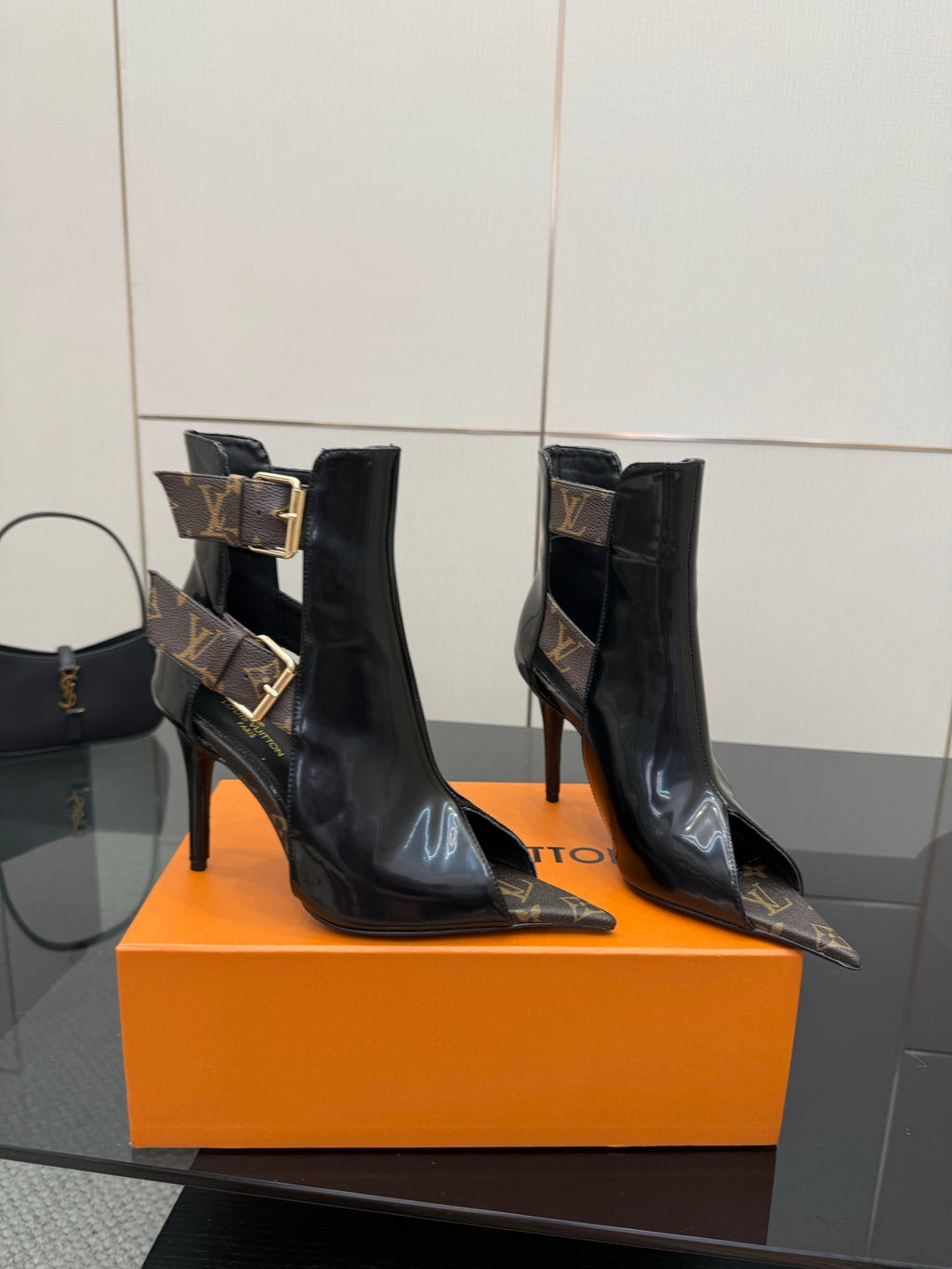 Pair of black patent ankle boots with stiletto heels and gold buckle straps.