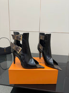 Pair of black patent ankle boots with stiletto heels and gold buckle straps.