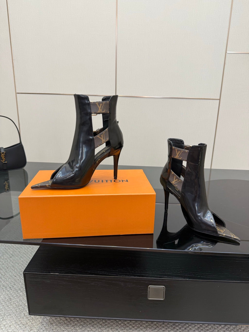 Black patent ankle boots with stiletto heels and gold buckle straps, pointed toe.