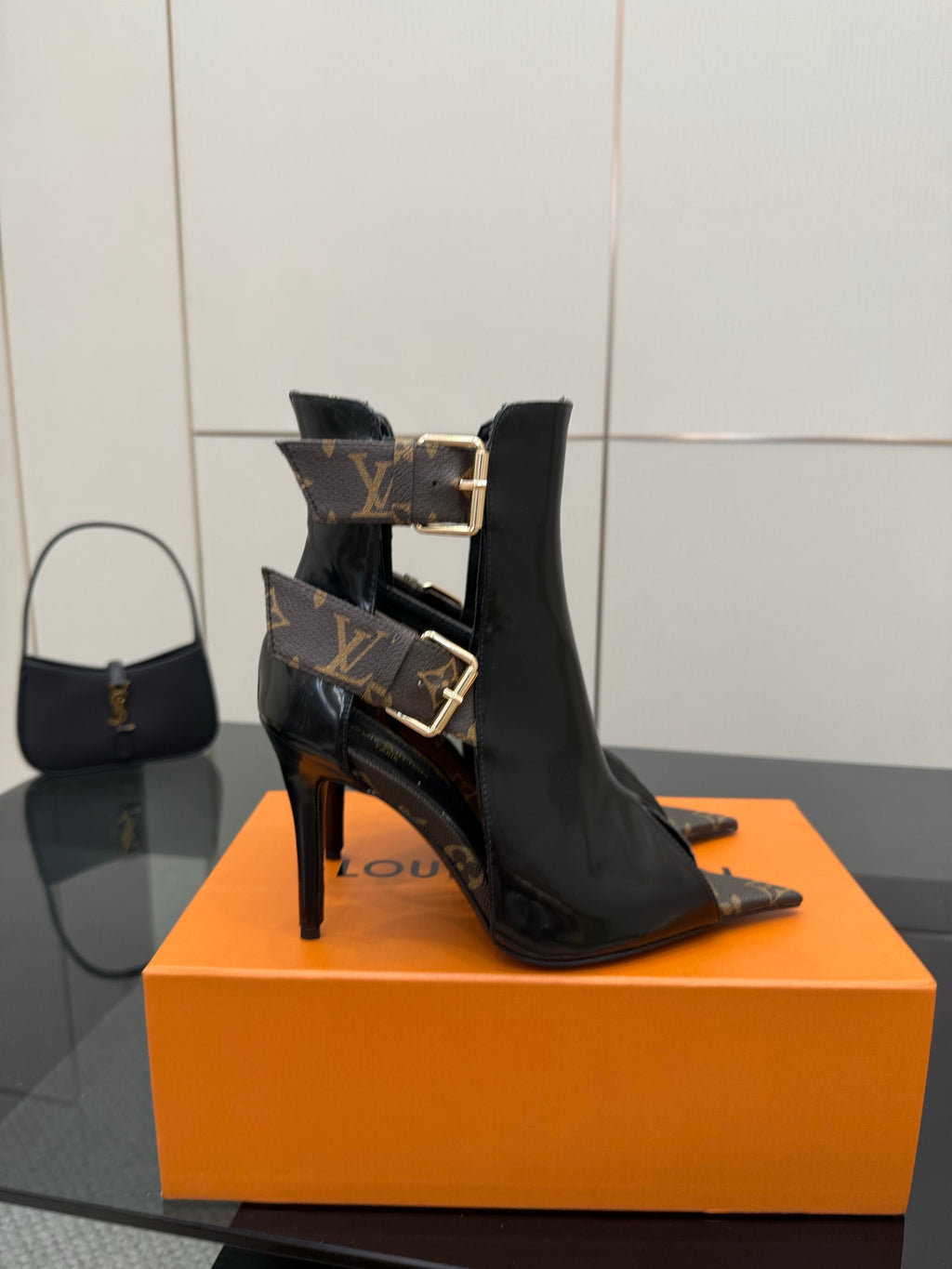 Black patent ankle boot with high stiletto heel and gold buckle detail strap.