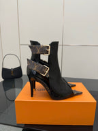 Black patent ankle boot with high stiletto heel and gold buckle detail strap.