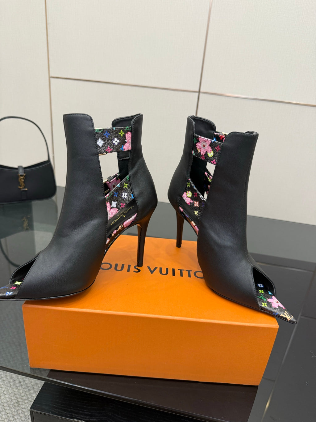 Pair of black ankle boots with floral side straps and gold-tone hardware.