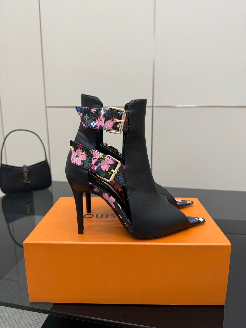 Black heeled ankle boots with multicolor floral straps and gold-tone buckle detail.
