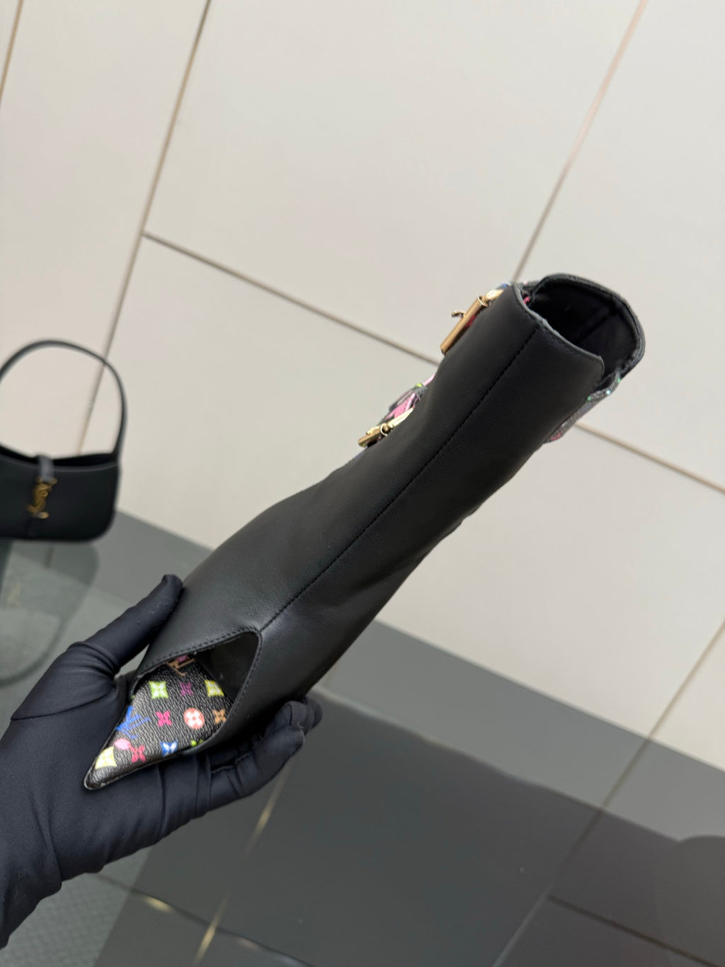 Single black ankle boot on hand, floral toe strap detail and slim heel.