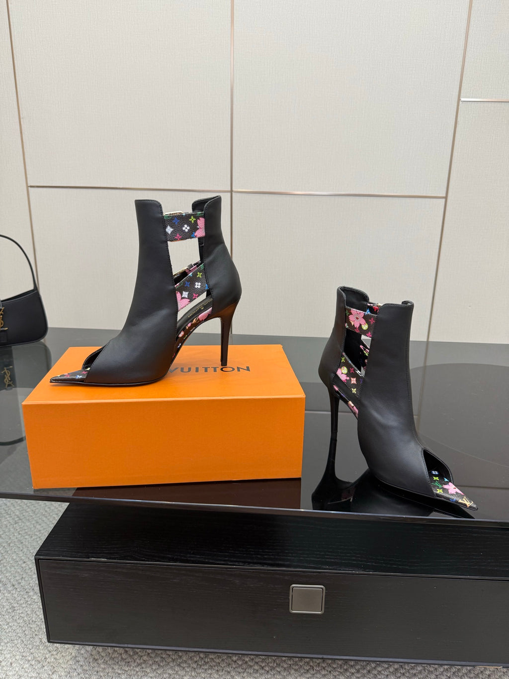 Black ankle boots with floral straps, gold buckle accents, and stiletto heels.