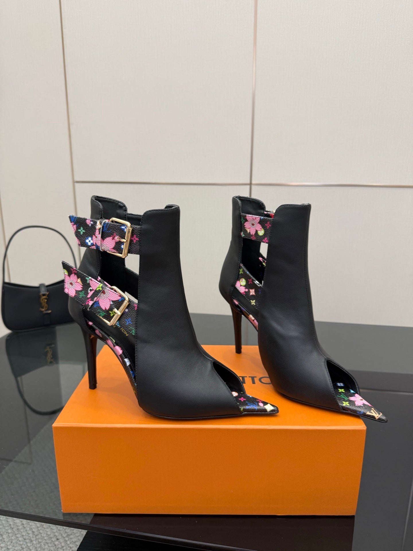 Black pointed-toe ankle boots with floral print straps and slim high heel.