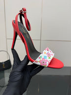 Louis Vuitton women’s red high-heel sandal held in hand; floral LV toe band and black straps