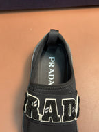 Prada unisex dark gray slip-on sneaker with PRADA logo on inner tongue.