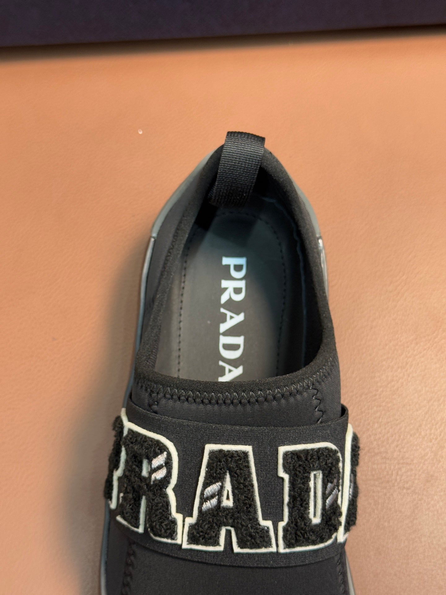 Prada unisex dark gray slip-on sneaker with PRADA logo on inner tongue.