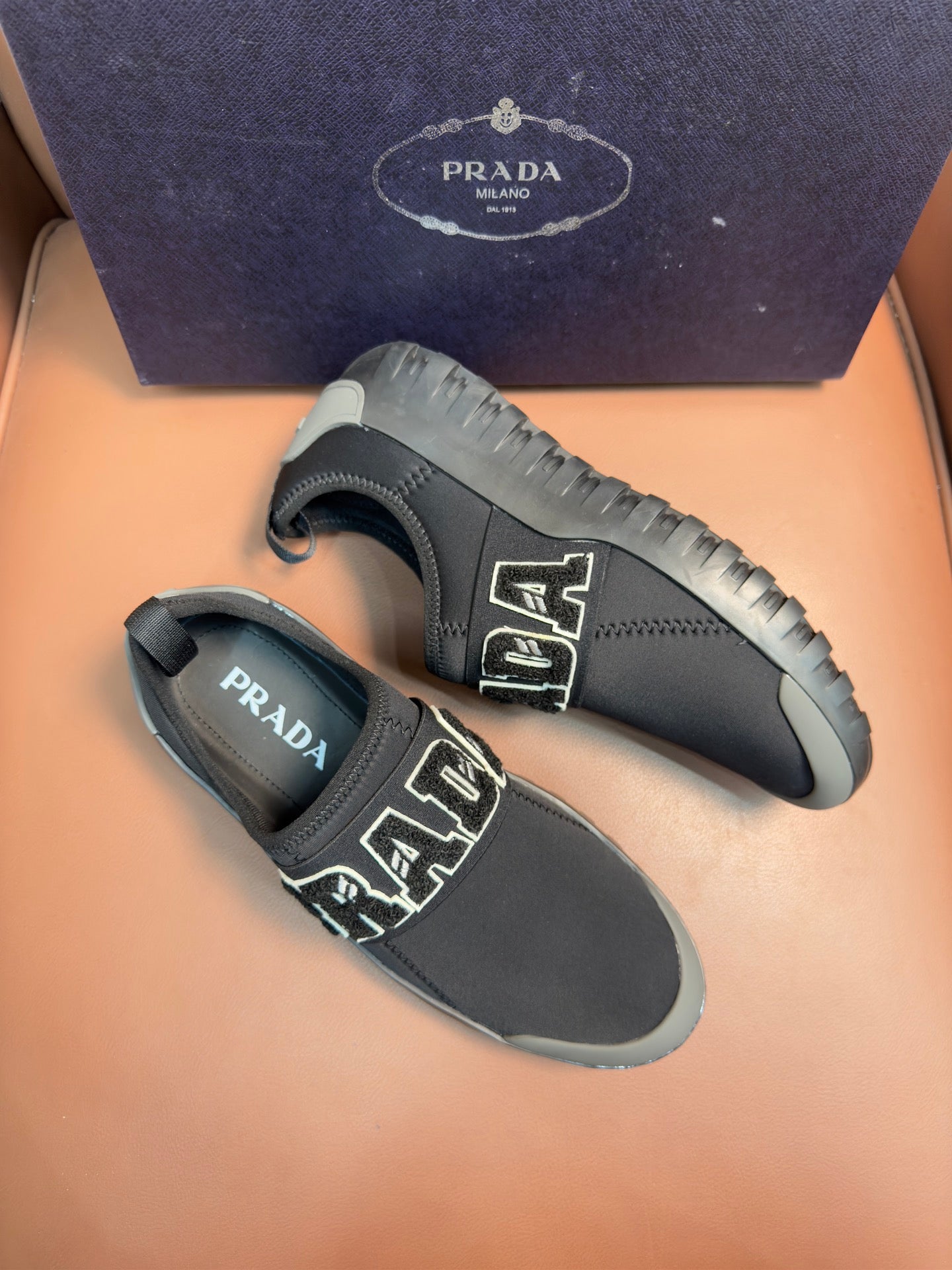 Prada unisex dark gray slip-on sneakers with PRADA logo patch and treaded sole.