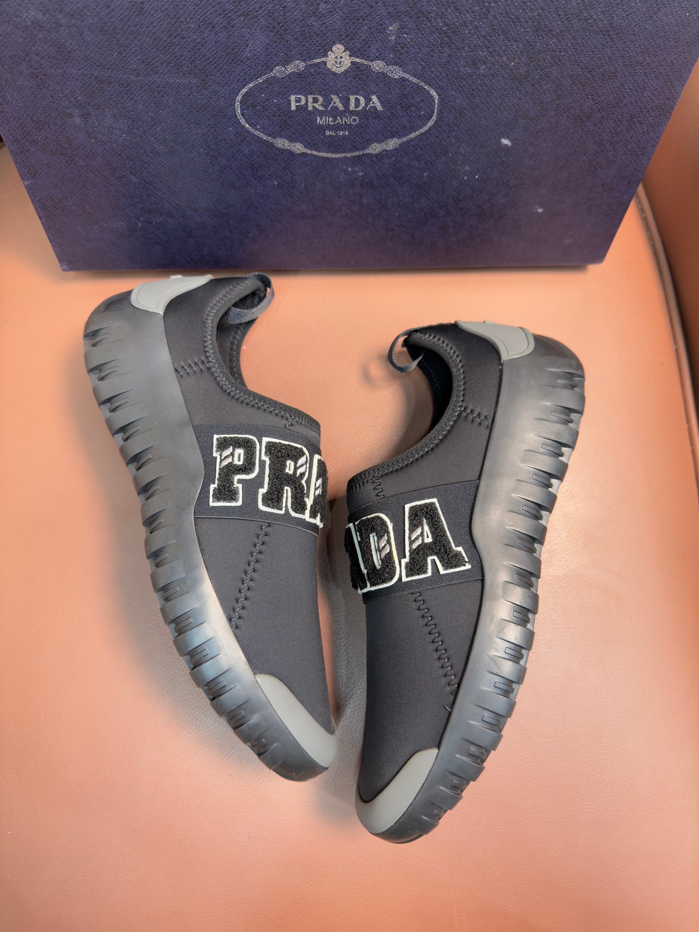 Prada unisex dark gray slip-on sneakers with PRADA lettering and cushioned collar.