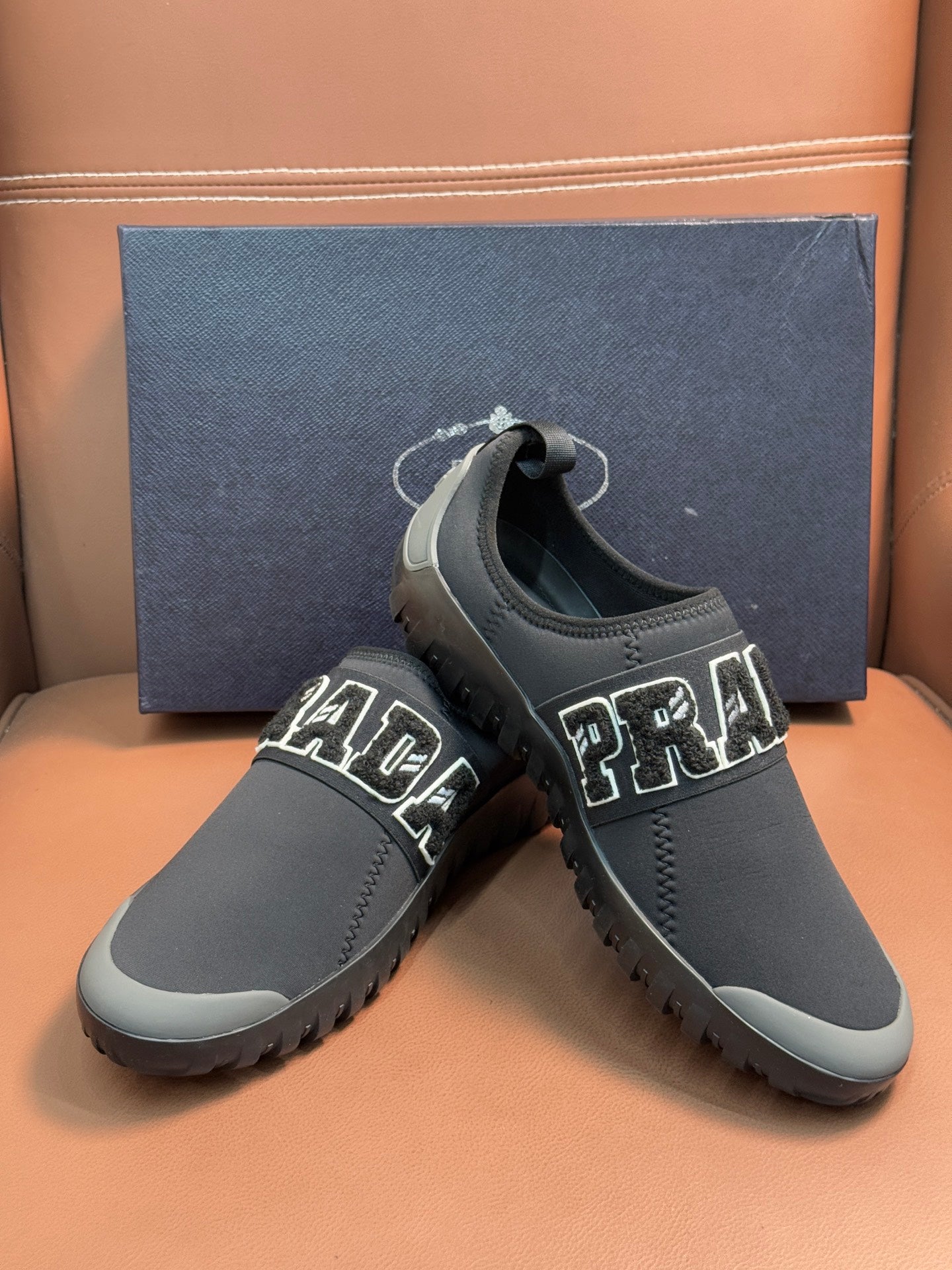 Prada unisex dark gray slip-on sneakers with PRADA lettering and elastic collar.