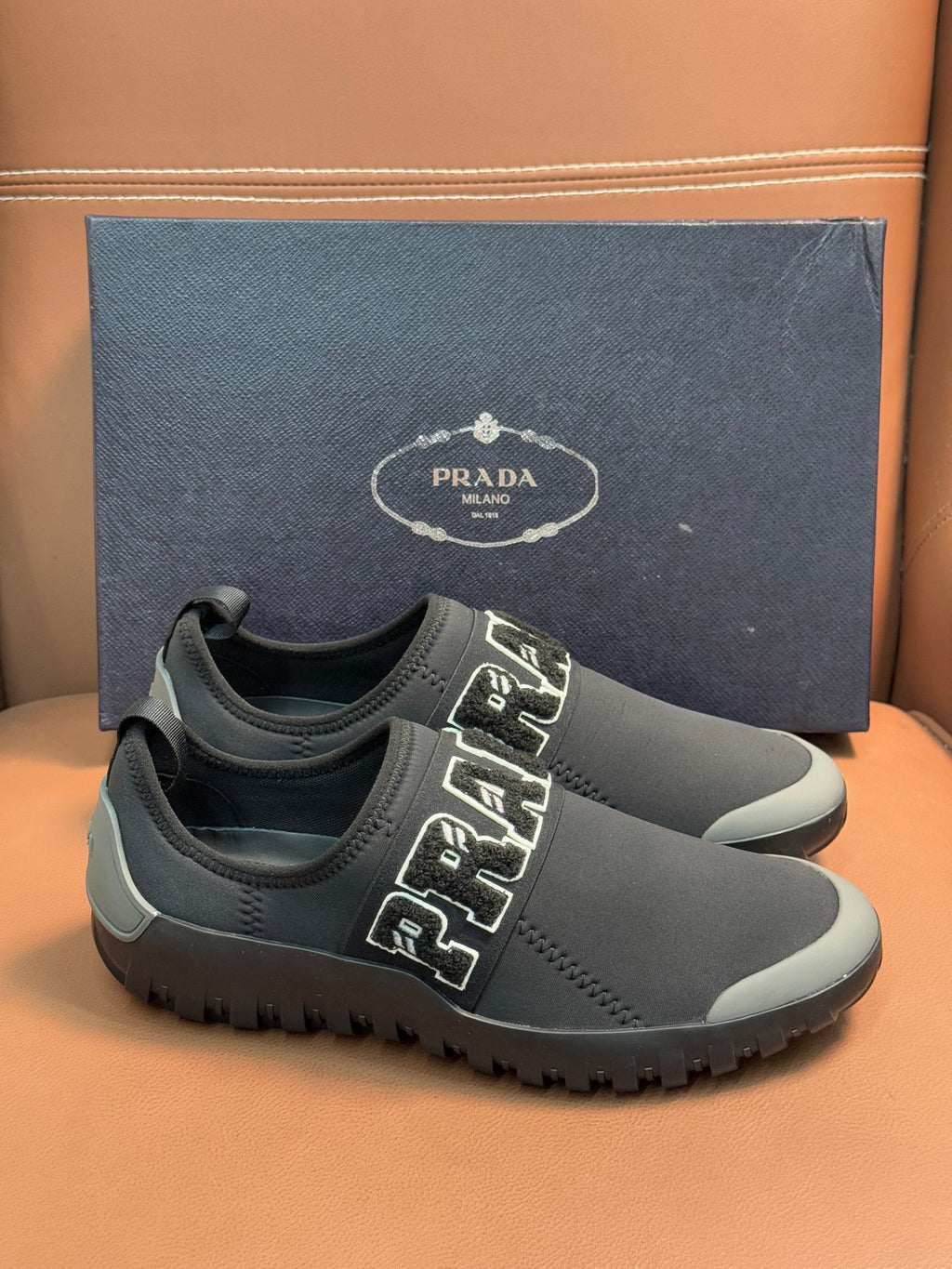 Prada unisex dark gray slip-on sneakers with PRADA strap detail and thick sole.