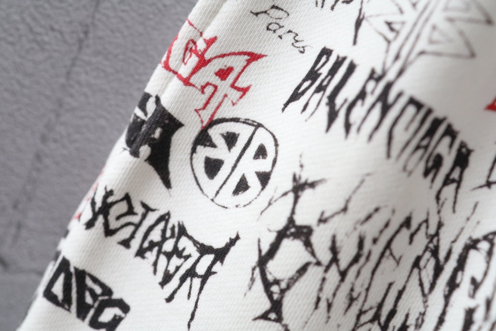 Balenciaga shorts side close-up with black logo icons and red accents on white