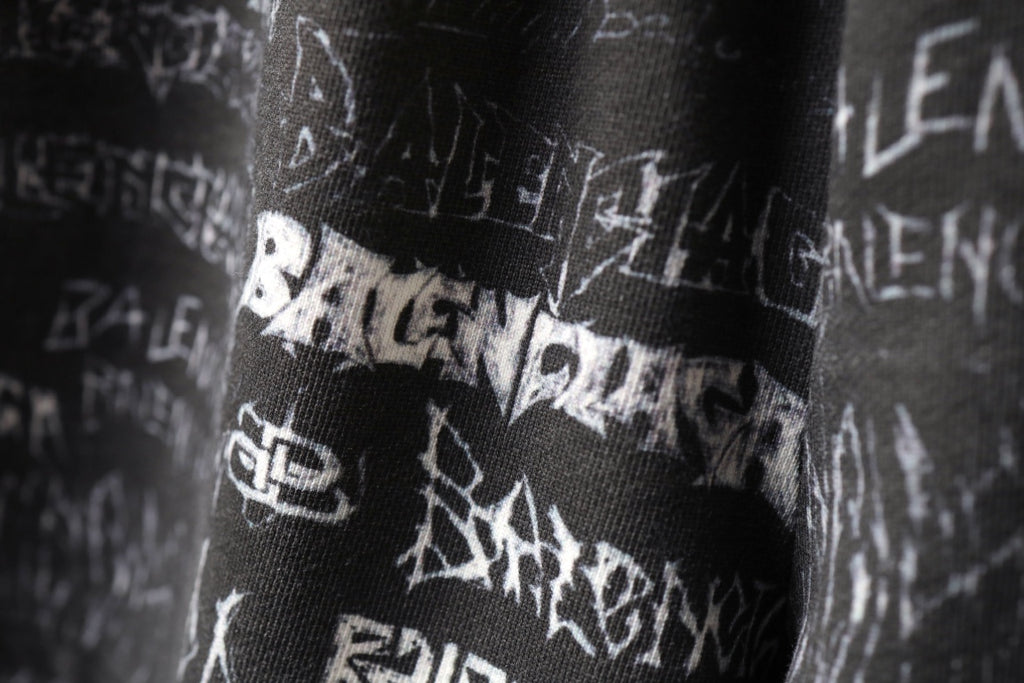 Balenciaga logo-print shorts close-up showing white symbols on black fabric.