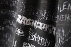 Balenciaga logo-print shorts close-up showing white symbols on black fabric.