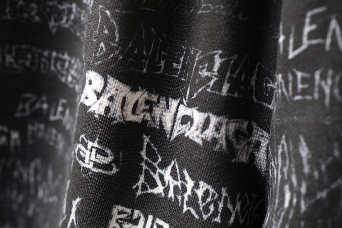 Balenciaga logo-print shorts close-up showing white symbols on black fabric.