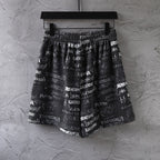 Balenciaga patterned shorts with allover white logo text and elastic waist, front view.