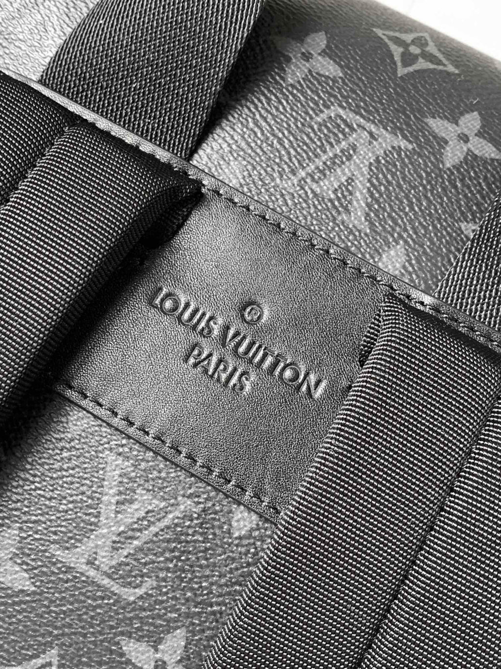 Louis Vuitton label patch stitched on dark monogram fabric strap