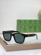 Gucci sunglasses with black frame and dark green-tinted lenses, front view