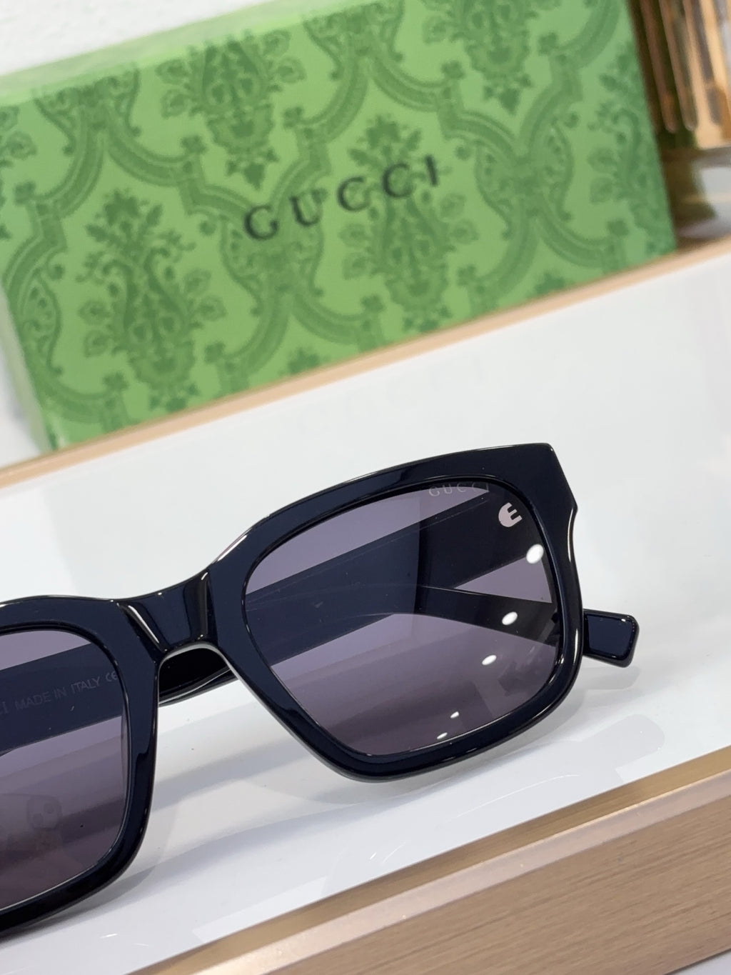 Gucci sunglasses with dark frame and purple-tinted lenses, close-up