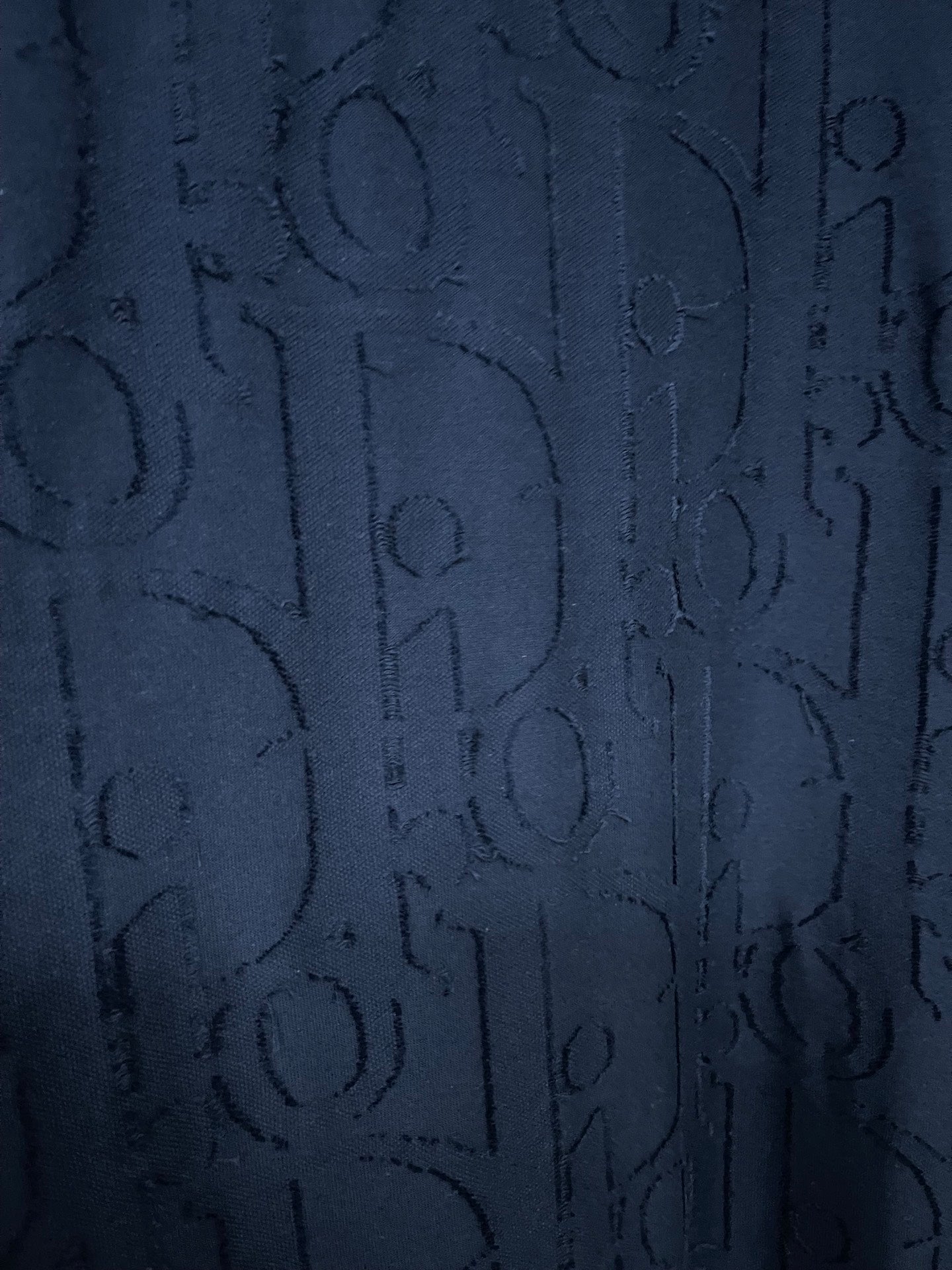 Dark blue Dior T-shirt fabric close-up with embossed allover logo pattern