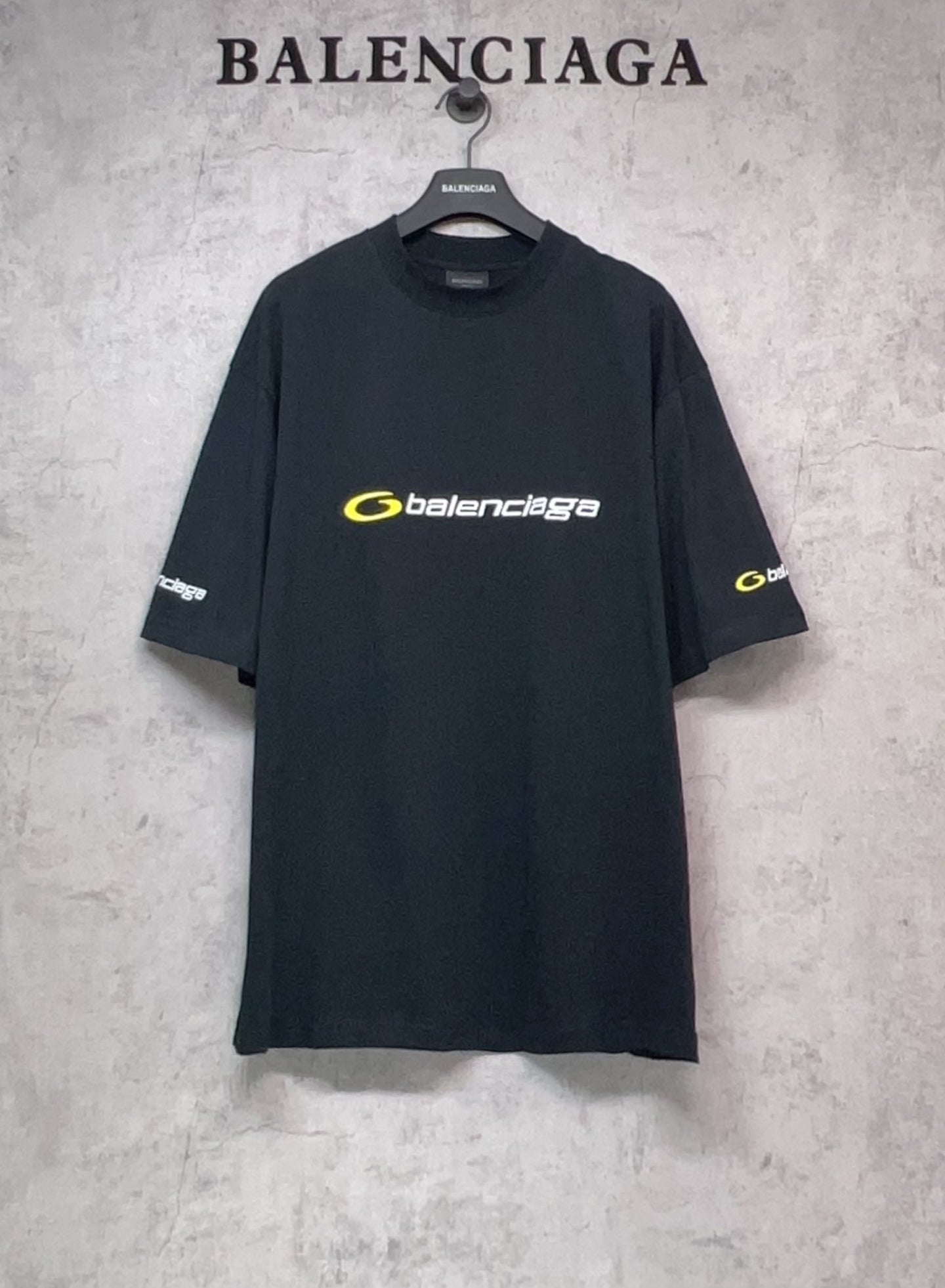 Dark T-shirt with crew neck, yellow Balenciaga logo on chest and sleeve prints