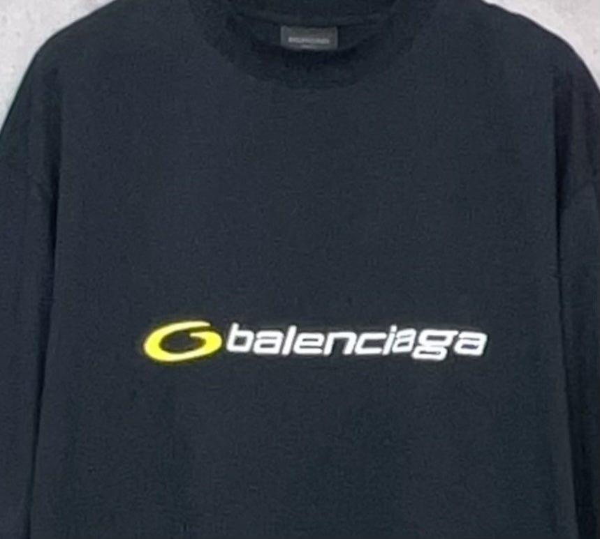 Dark T-shirt close-up with yellow Balenciaga logo across the chest