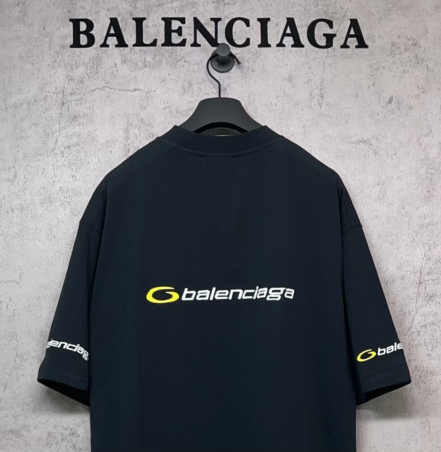Dark Balenciaga T-shirt back view with yellow logo and sleeve logo patches