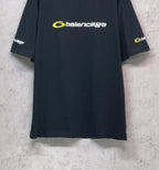 Dark T-shirt on hanger with yellow Balenciaga logo on the front and sleeve prints