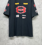 Dark navy short-sleeve T-shirt front view with red B emblem and multiple logo patches.