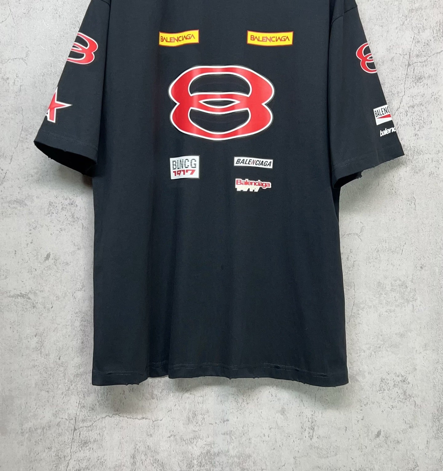 Dark navy short-sleeve T-shirt front view with red B emblem and multiple logo patches.