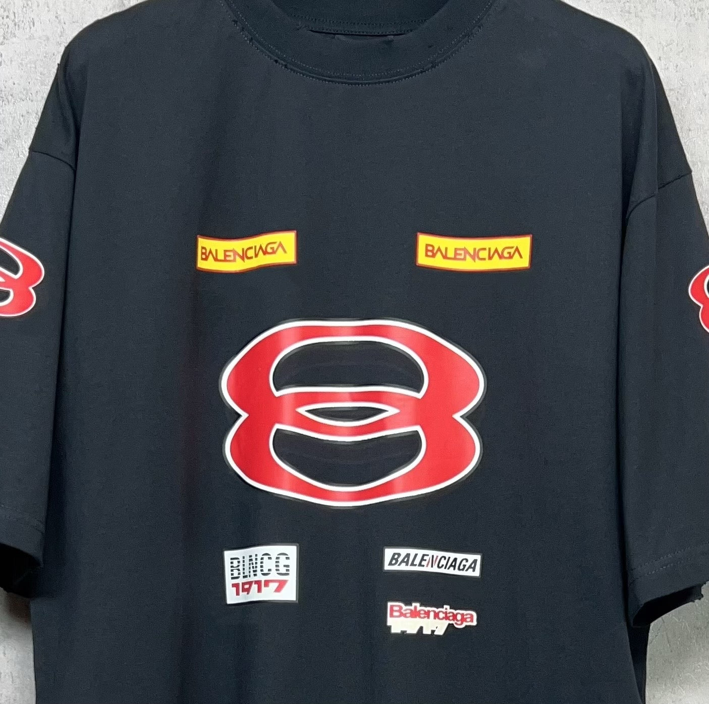Dark navy short-sleeve T-shirt close-up with red B graphic and small stacked logo prints.