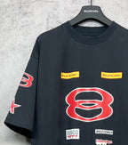 Dark navy short-sleeve T-shirt close-up with red B emblem and yellow logo nameplates.