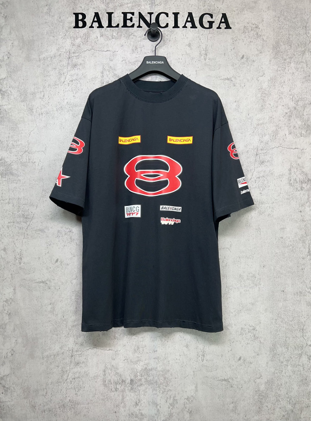 Dark navy short-sleeve T-shirt with large red B graphic and multicolor logo patches.
