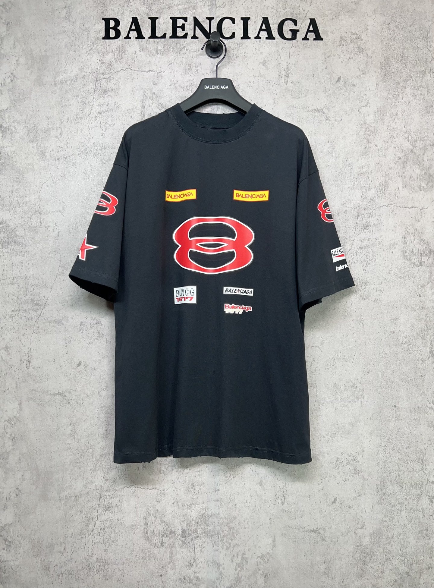 Dark navy short-sleeve T-shirt with large red B graphic and multicolor logo patches.